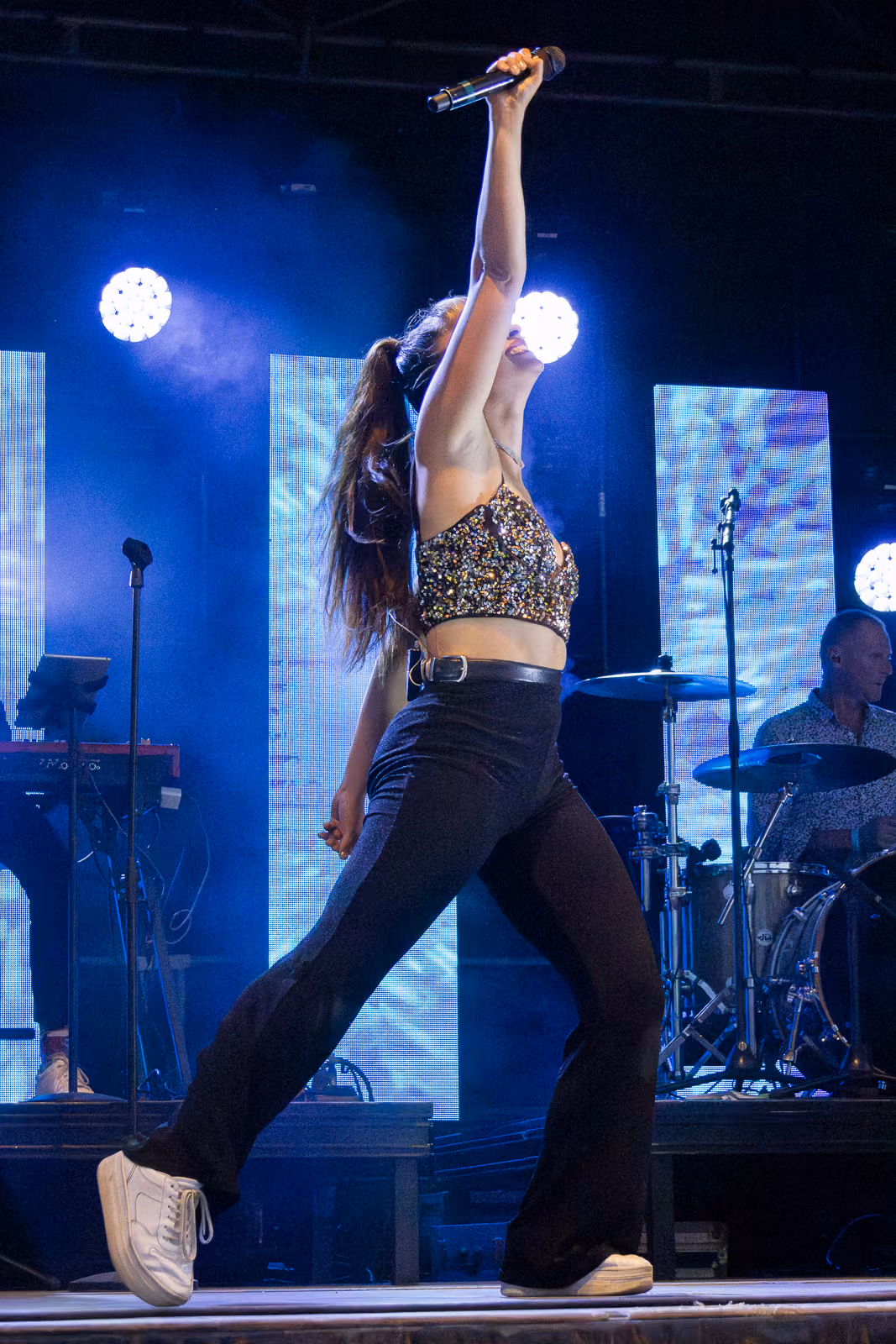 Chanteuse bras levé sur une scène éclairée en bleu, photographie de concert par Tony Delage